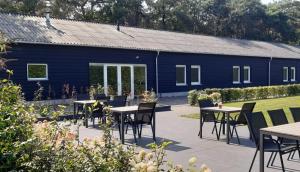 ein blaues Gebäude mit Tischen und Stühlen im Garten in der Unterkunft Hotel B&B Buiten Loon in Loon op Zand