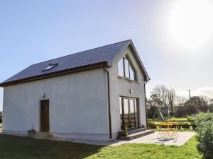 um pequeno edifício branco com uma mesa num quintal em Sunset View Lodge em Fethard-on-Sea
