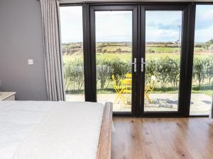 1 dormitorio con 1 cama y puerta corredera de cristal en Sunset View Lodge, en Fethard-on-Sea