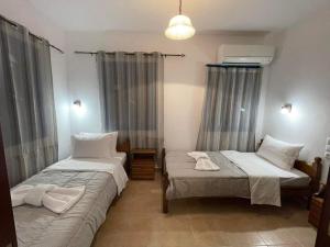 two beds sitting in a room with curtains at LUNAR MELODY in Karpathos