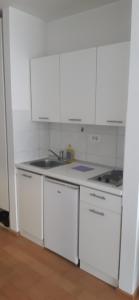 eine Küche mit weißen Schränken und einer Spüle in der Unterkunft Apartman M in Mostar