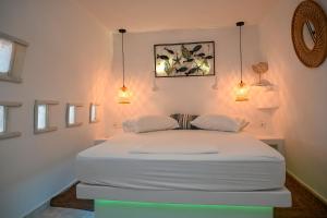 Cama blanca en habitación con 2 luces en kleris apartments 8, en Tinos