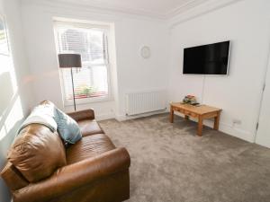 a living room with a brown leather couch and a tv at Bodnant in Llandudno