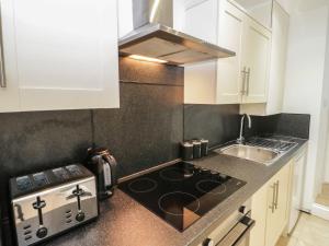 a kitchen with a stove top oven next to a sink at Bodnant in Llandudno