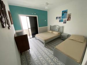 グアルジャにあるApartamento no Guarujá, a poucos minutos da praiaのベッド2台と窓が備わる小さな客室です。