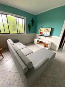 a living room with a couch and a tv at Apartamento no Guarujá, a poucos minutos da praia in Guarujá