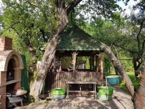 a gazebo with a bench under a tree at Cazare La Oana in Haţeg