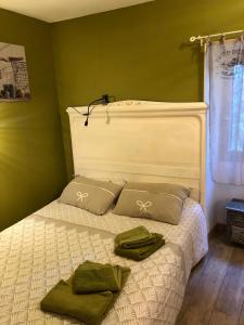 a bed with two green towels on top of it at Havre de paix en Provence in Lauris