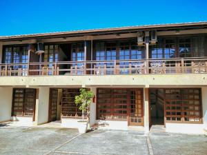 a building with wooden doors and a balcony at Pousada Bangalôs Da Mole - Florianópolis in Florianópolis