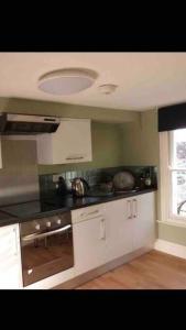 een keuken met witte kasten en een fornuis met oven bij Abbotts Mews Apartment York City Centre in York