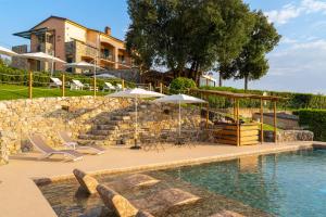 una piscina con sedie e ombrelloni di fronte a una casa di Golfo dei Poeti Relais & Spa ad Ameglia