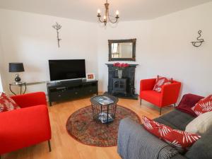 a living room with red chairs and a television at 1 Closheen Lane in Rosscarbery