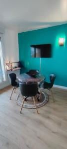een kamer met een tafel en stoelen en een groene muur bij Soleil, Vue & Confort à Tara in Port-Vendres