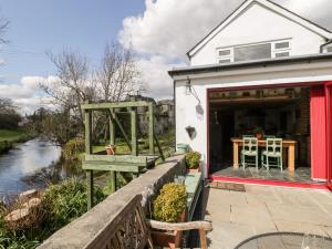 a cottage with a deck with a table and chairs at Riverside 67 Dorchester Road in Dorchester