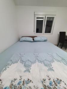 een bed met een blauwe en witte deken erop bij Apartman Tolosi 2 in Podgorica