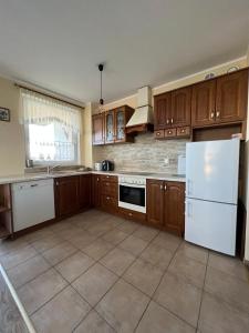 a kitchen with wooden cabinets and a white refrigerator at Cozy apartment close to Gdansk & Airport in Gdańsk