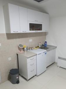 een keuken met witte kasten en een aanrecht bij Apartman Tolosi 2 in Podgorica