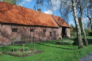 an old brick barn with an orange roof at La Roulotte des Mohuques in Mont-Saint-Aubert