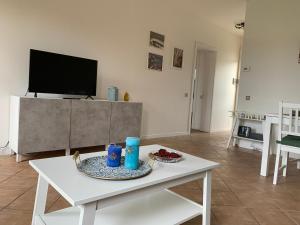 uma sala de estar com uma mesa branca e uma televisão em Casa Biancoliva em Toscolano Maderno