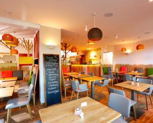 a restaurant with wooden tables and chairs and a chalkboard at Flux-Biohotel Werratal in Hannoversch Münden