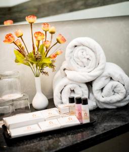 a bathroom counter with towels and a vase with flowers at Hotel Platinum Shravasti in Katra