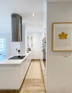 una cocina con armarios blancos y una foto en la pared en Precioso piso nuevo dentro del recinto amurallado en Lugo