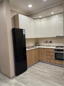 トビリシにあるLuxury Tower Saakadzeのキッチン(黒い冷蔵庫、木製キャビネット付)