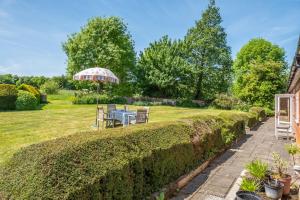 a garden with a table and an umbrella at Charming cottage in beautiful countryside with a boating lake - The Calf Pens in Ipswich