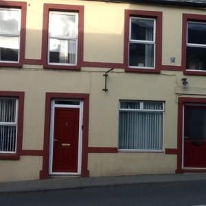 a building with red doors and windows on a street at Noreen Seans in Carndonagh
