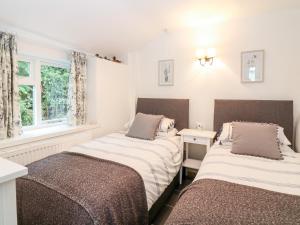 a bedroom with two beds and a window at Shepherds Cottage in Dulverton