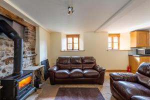 sala de estar con sofá de cuero y chimenea en Chapel Beck, Millthrop, en Sedbergh