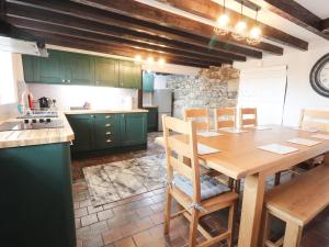 a kitchen with green cabinets and a wooden table at Cae Adar Farm in Wrexham