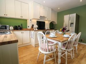 a kitchen with a wooden table and white cabinets at 1 Foresters Rest in Alton