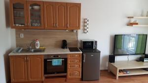 a kitchen with wooden cabinets and a sink and a tv at Apartmány Liptov MACO in Liptovský Mikuláš
