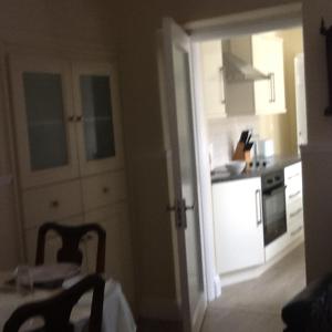 a kitchen with white cabinets and a table and chairs at Noreen Seans in Carndonagh
