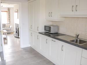 a white kitchen with a sink and a microwave at C64 Cahermore Holiday Village in Enniscrone