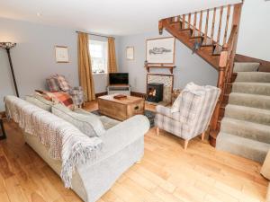 a living room with two couches and a staircase at Sarah's Cottage in Morpeth