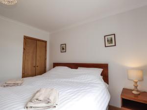 sypialnia z białym łóżkiem z ręcznikiem w obiekcie Boatman's Cottage w mieście Coillemore