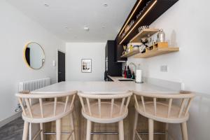 a kitchen with a white counter and two bar stools at The Battersea Secret - Trendy 3BDR Flat with Patio in London