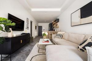 uma sala de estar com um sofá branco e uma televisão em The Battersea Secret - Trendy 3BDR Flat with Patio em Londres