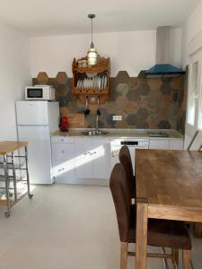 eine Küche mit weißen Geräten und einem Holztisch in der Unterkunft El principito in Vejer de la Frontera