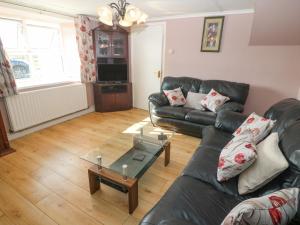 a living room with a black leather couch and a table at Gleann Griannmhar in Rosscarbery