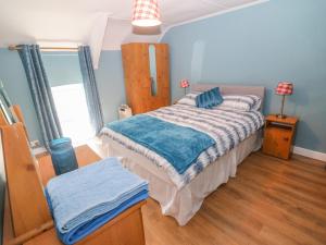 una camera da letto con letto, pareti blu e pavimenti in legno di Gleann Griannmhar a Rosscarbery