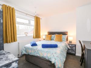 ein Schlafzimmer mit einem Bett mit blauen Laken und einem Fenster in der Unterkunft Rose Cottage in Skegness