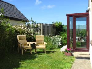 two chairs and a table in a garden at Ty Aelwyd in St. Davids +8 photos