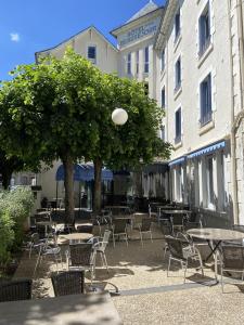 un groupe de tables et de chaises devant un bâtiment dans l'établissement Hotel Beauséjour, à Vic-sur-Cère