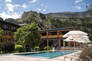 a hotel with a pool and chairs and a mountain at Hotel Post in Prutz