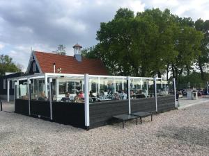 un groupe de personnes assises à des tables dans un bâtiment dans l'établissement Fraai Tiny House aan het veluwemeer met uitzicht & veranda, à Hulshorst