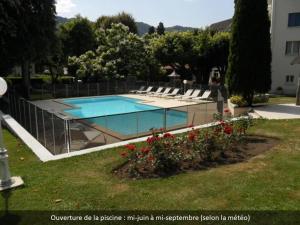 a swimming pool with lounge chairs in a yard at Hotel Beauséjour in Vic-sur-Cère