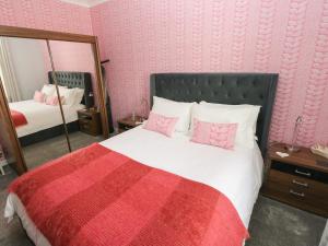 a bedroom with a bed with a red blanket and a mirror at Holly Cottage in Pembroke